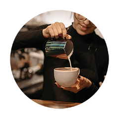 Barista pouring steamed milk into espresso to create smooth latte art and handcrafted specialty coffee.