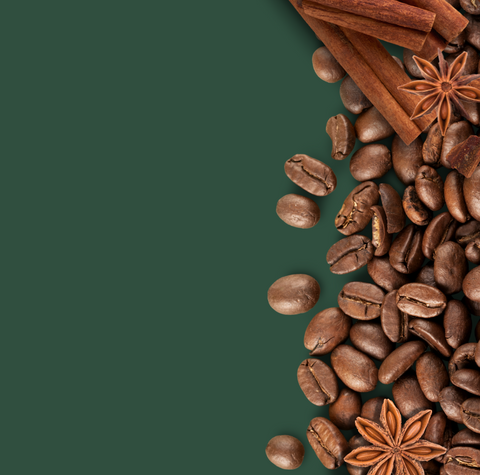 Roasted coffee beans with cinnamon sticks and star anise on a green background, representing rich flavors and aromatic specialty coffee.