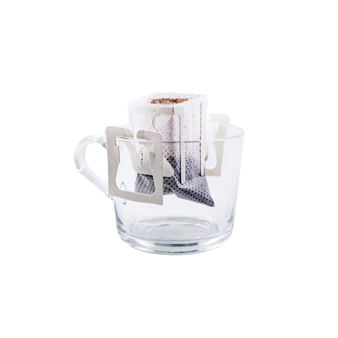 Coffee drip bag attached to a clear glass mug for easy single-cup pour over coffee brewing at home or the office.