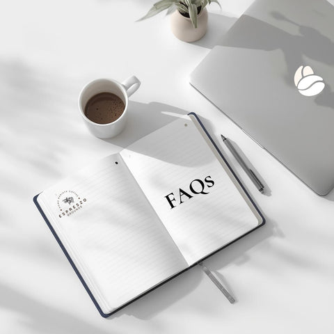 Open notebook with 'FAQs' on a desk with a laptop and coffee cup.