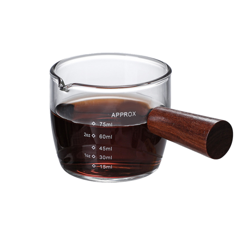 A clear glass coffee cup with a brown handle and measurement markings, filled with coffee.